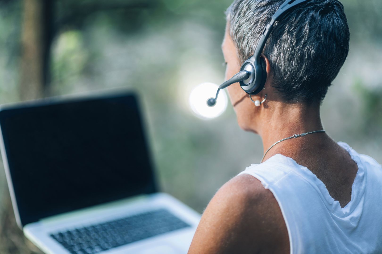 Remote work. Positive middle-aged woman working remotely, wearing a headset, talking