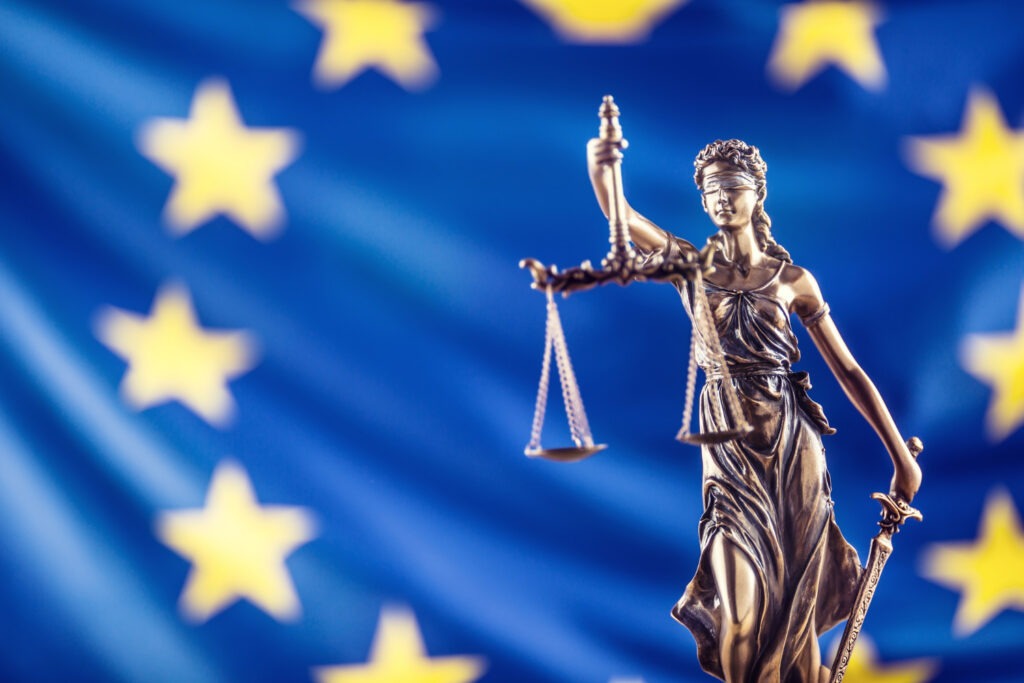 Statue de la justice devant un drapeau de l'Union européenne, symbolisant la réglementation et la cybersécurité avec la directive NIS